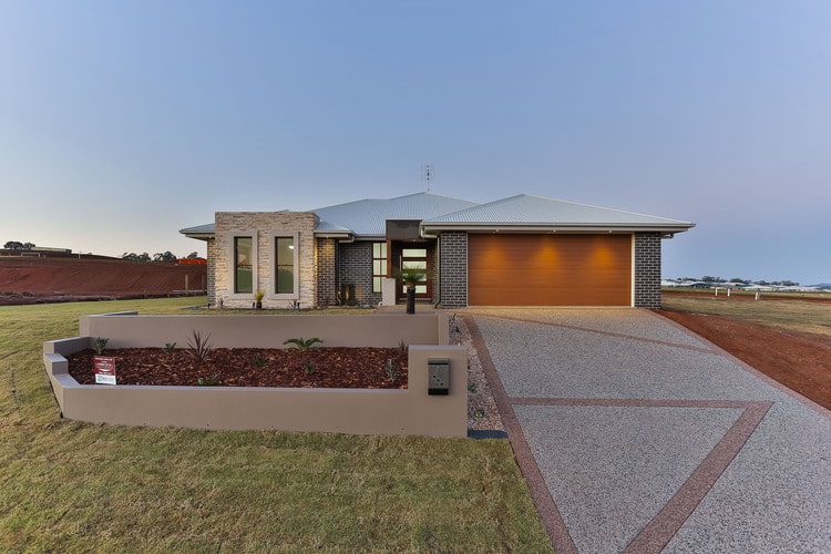 Grey brick house with stone feature wall and pebble concrete driveway