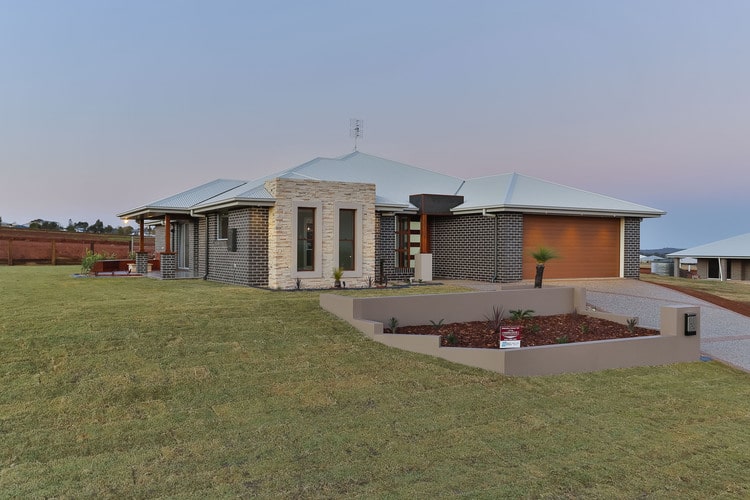 Outdoor view of grey brick home with stone feature wall