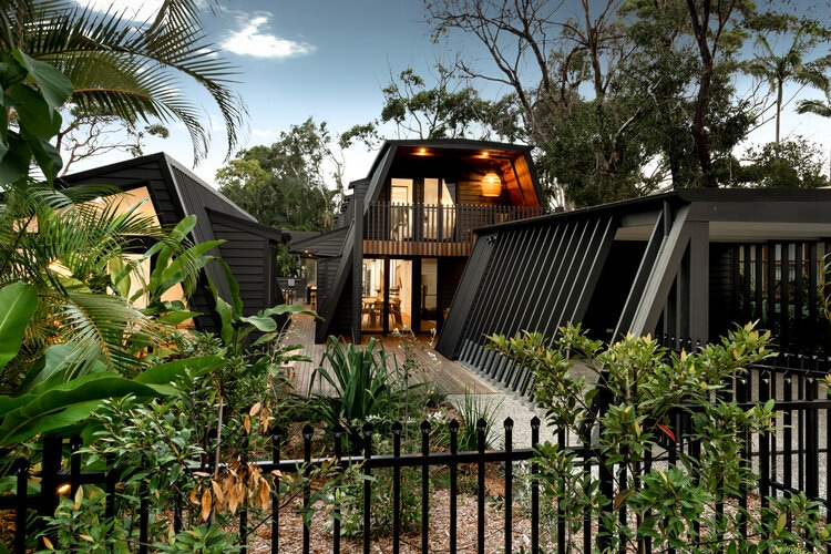 A frame grey house with lights and flora