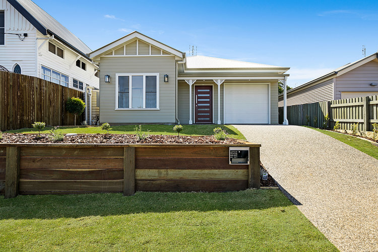 Grey house with brown door and pebble driveway