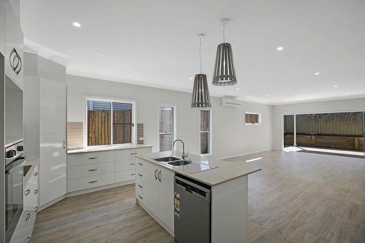Open plan kitchen with white walls and floating timber floors