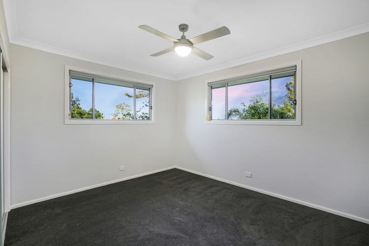 White bedroom with grey floors and ceiling fan