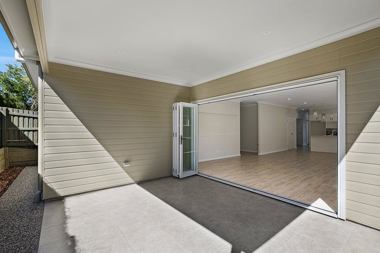 Backyard patio area with brown weatherboard walls