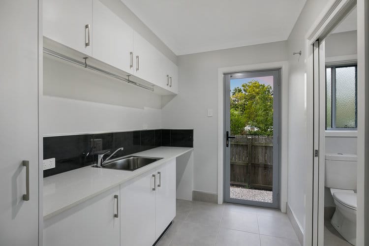 White laundry with overhead cupboards and toilet