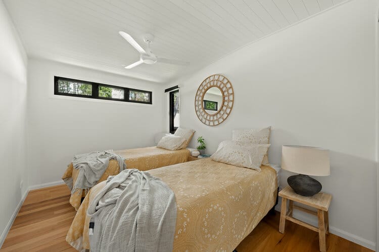 Timber floored bedroom with white walls and brown single beds