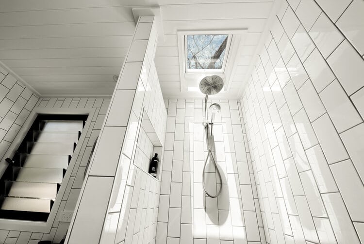White bathroom with silver showerhead and skylight