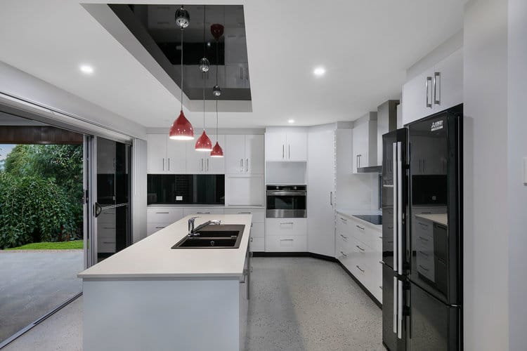 White and grey kitchen with black fridge and sliding door