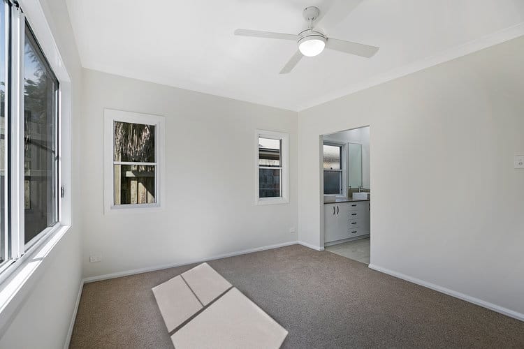 Empty white room looking onto kitchen area