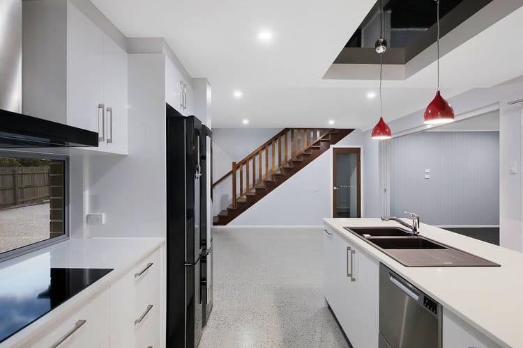 White kitchen looking at timber stairs and roof feature