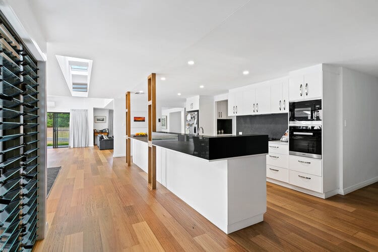 White kitchen with dark benchtops and timber floors