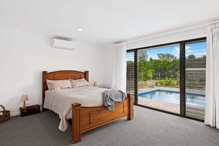 White bedroom with grey carpets and wide open widows
