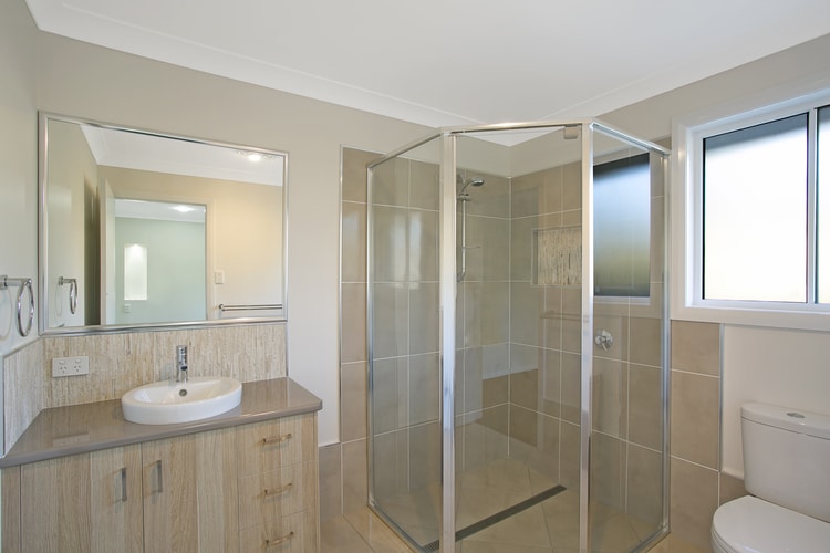 Small bathroom featuring shower, toilet and vanity in browns and greys