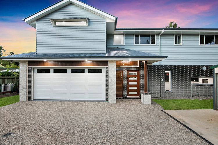 New grey brick and blue weatherboard home with white rollerdoor