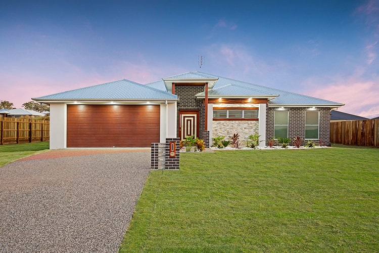 Front view of house featuring brown roller door, dark brick and silver roof