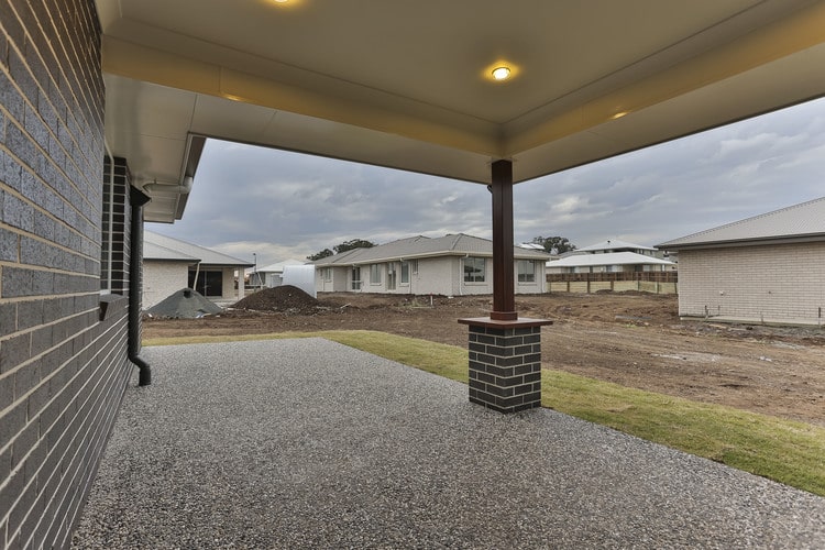 Backyard of grey brick home with pebblestone on concrete