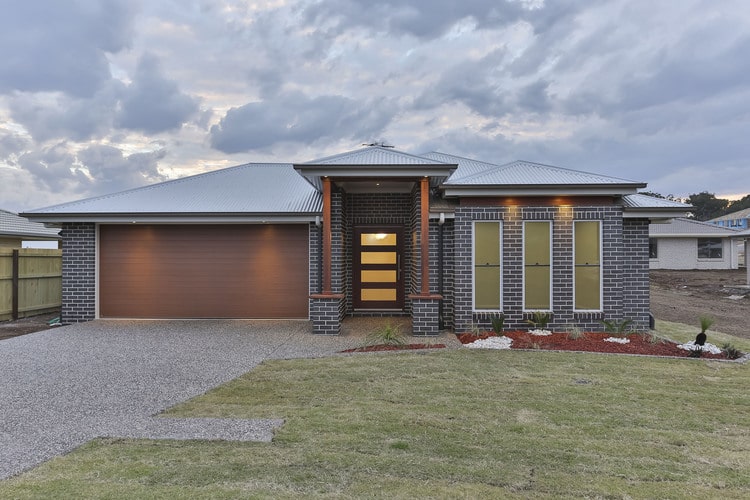 Front view of dark brick home with timber entry way and front door