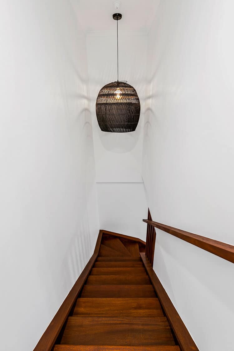White hallway with brown stairs and brown light
