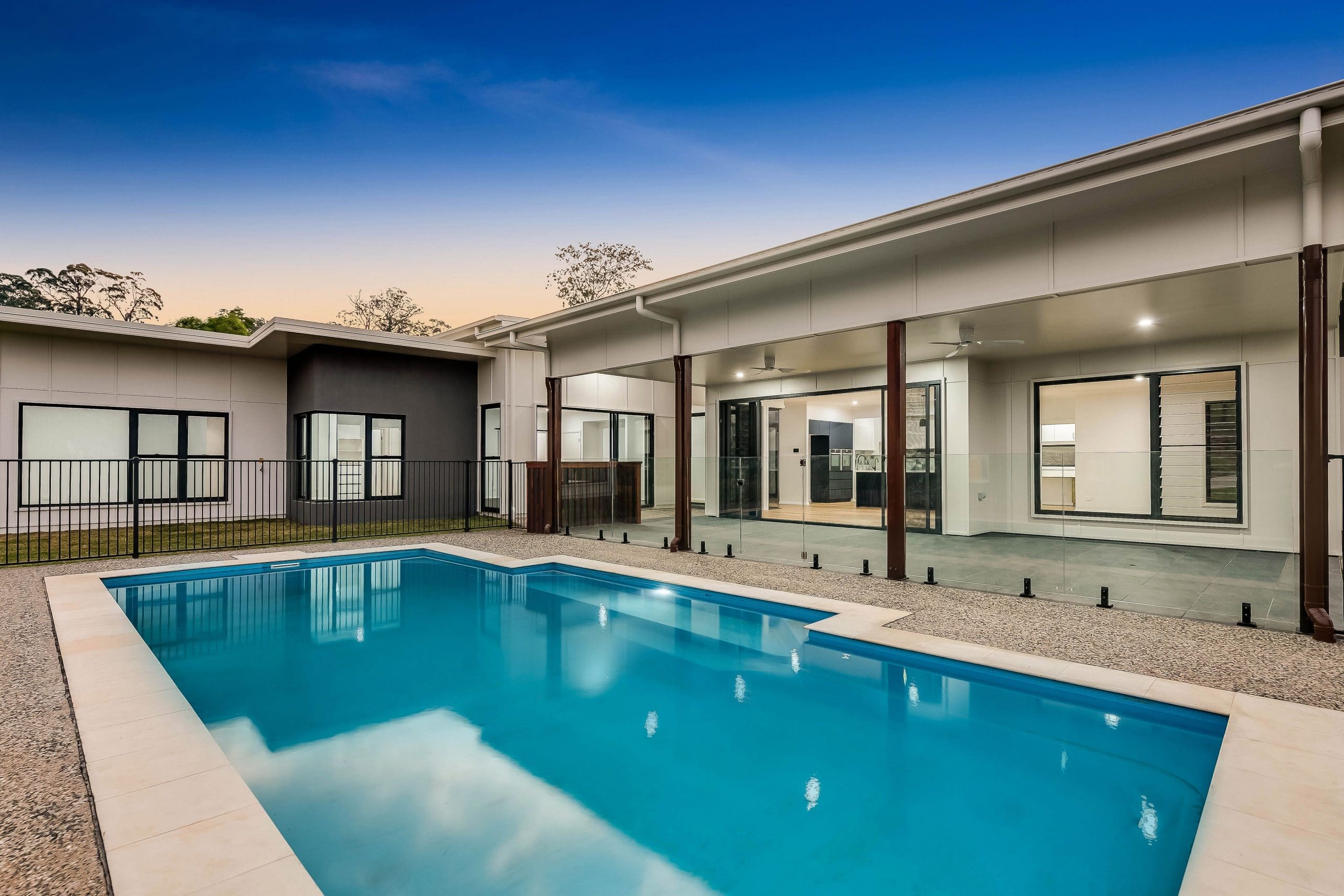 Outdoor view of pool, with grey, white and brown house