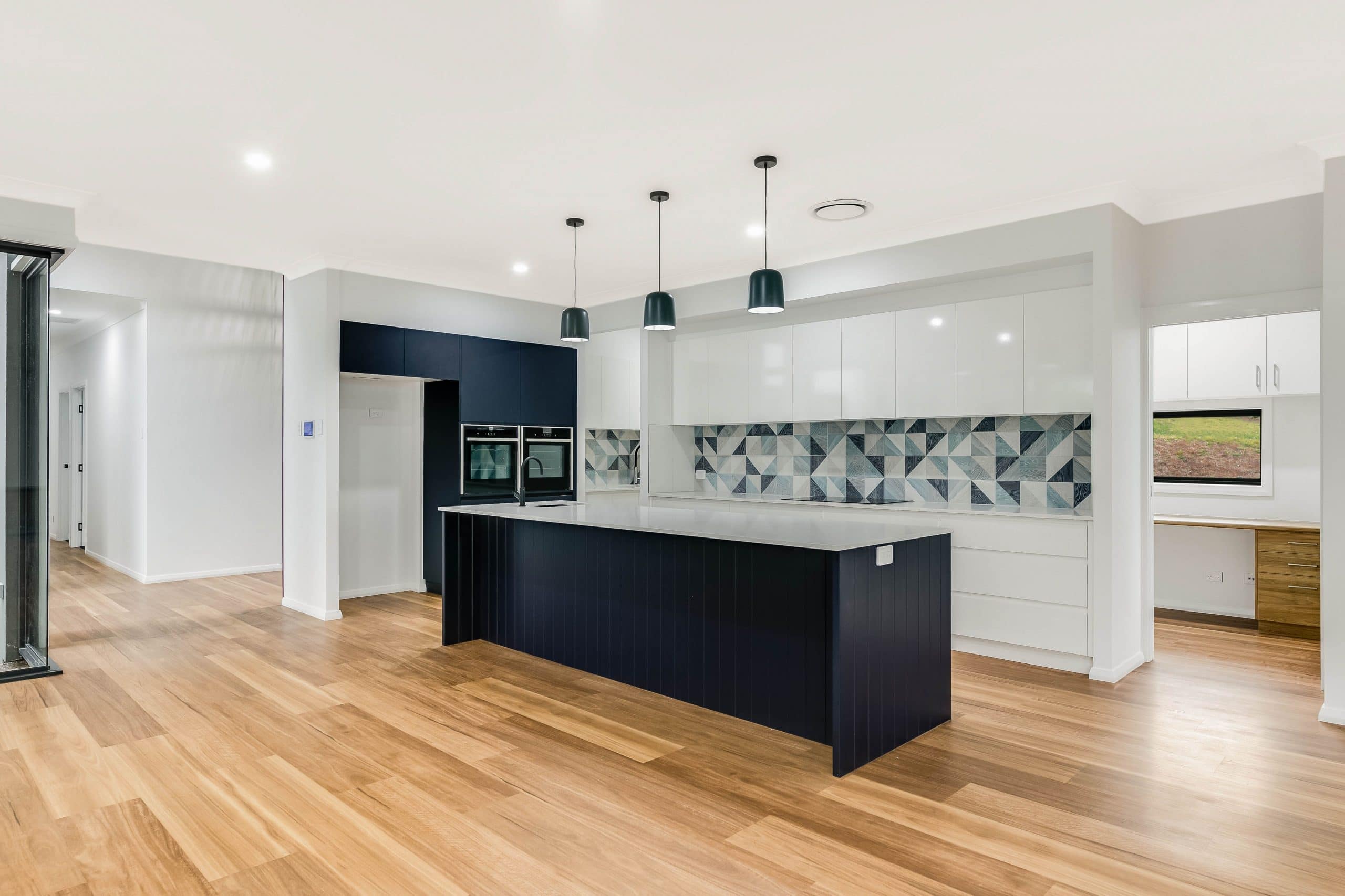 Navy blue kitchen with wooden floors, with open office and hallway doors