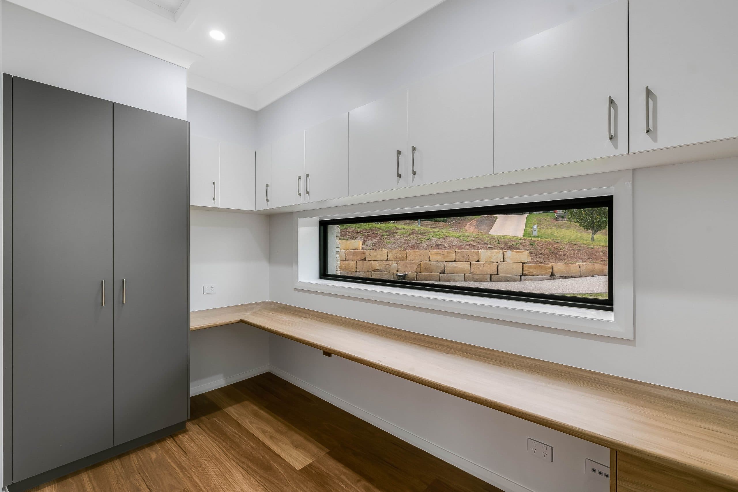 An office with white cupboards and grey closet, with timber desktops