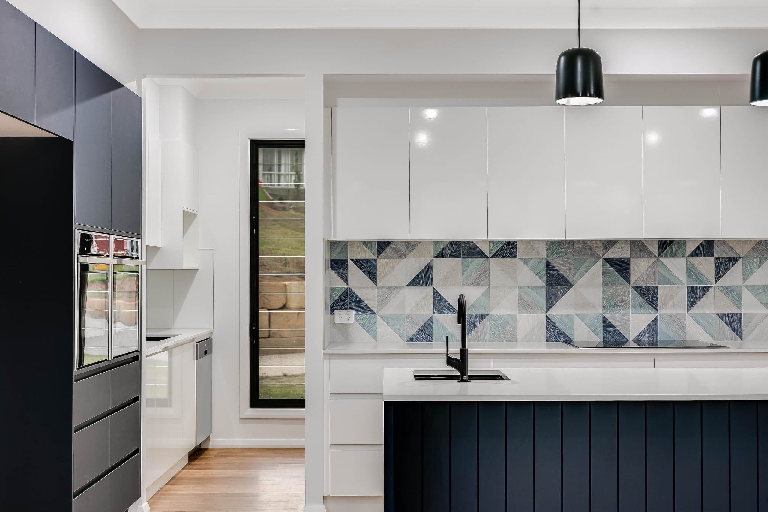 A blue tiled kitchen with a dishwasher and oven and open window